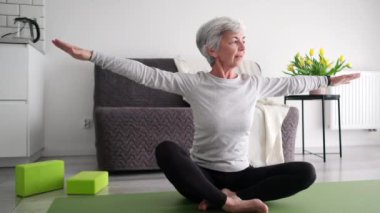 Evde spor yapan çekici yaşlı bayan ve yoga egzersizleri yapıyor.
