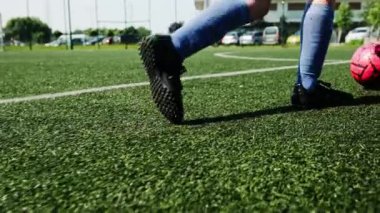 Genç Oyuncu antrenman sırasında futbol sahasında top sürüyor.