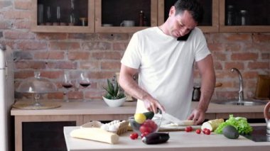 Genç adam telefonda konuşurken mutfakta sağlıklı bir kahvaltı hazırlıyor.