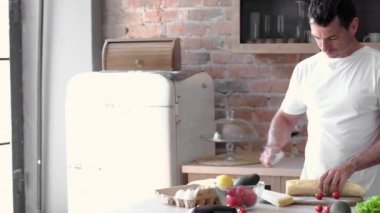 Mutfakta ekmek kesen adam, üssü sağlıklı bir kahvaltıya hazırlar.