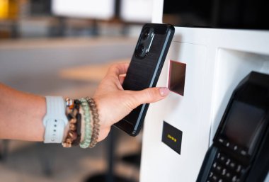 Kız, Qr kodunu self servis terminalinde taramak için akıllı telefon kullanıyor