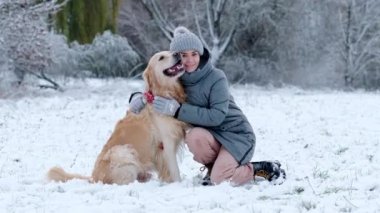 Kışın kar yağarken güzel köpeğine sarılan bir kız.