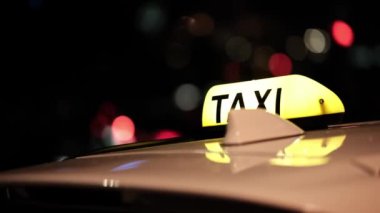 Taksi tabelasının ışığı ve taksi arabasının gece şehirde dolaşması.