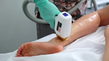 Kız, daha pürüzsüz bir cilt için kaplıca kliniğinde bacak kıllarını aldırıyor.