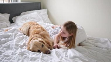 Neşeli genç kız, yatak odasındaki altın av köpeğiyle eğleniyor.