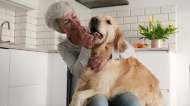 Neşeli yaşlı bayan mutfaktaki güzel köpeğiyle eğleniyor.