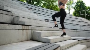 Parkta spor yapan ve merdivenlerden koşarak çıkan formda bir kız.