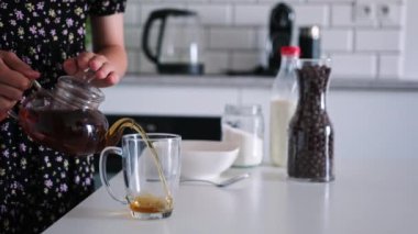 Küçük kız mutfakta kahvaltıda siyah çay yapıyor.