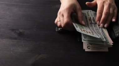 Siyah bir cüzdandaki paraya bakan ve bazı Amerikan dolarlarını çalan bir kız.