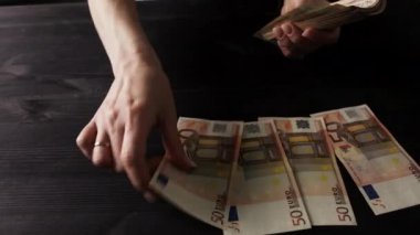 Masadaki 50 Euro 'luk banknotları sınıflandıran ve sayan kadın.