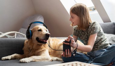 Şirin, küçük gülümseyen kız, Akıllı Telefon Ekranı 'nı Golden Retriever' a gösteriyor.