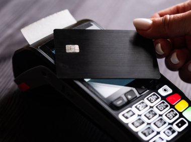 Kız ödemeyi bir kablosuz güç terminali kullanarak kredi kartıyla yapıyor.