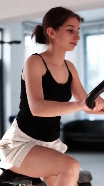 Dikey bir videoda spor salonunda bisiklet eğitmeniyle kız eğitimi