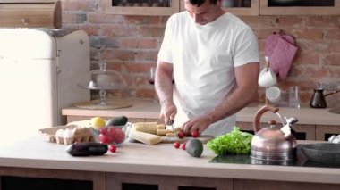 Genç adam mutfakta parmesan peyniri kesti, sağlıklı bir diyet yemeği hazırladı.