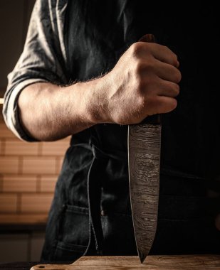 Şef önlüklü, elinde bıçakla mutfak tahtasına vuruyor. Lokanta aşçılık aracı ile proffesional