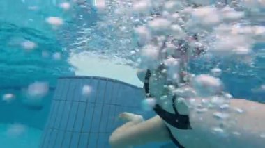 Havuza dalan genç bir kız Şnorkel maskesi takıp kendini filme çekiyor.