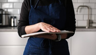 Mutfakta yemek tarifi kitabını arayan bir kadın.