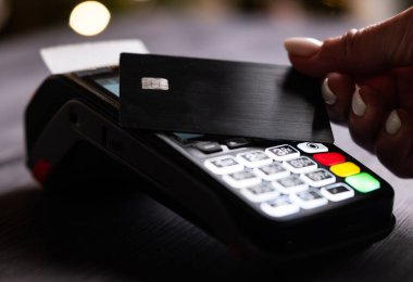 Kredi kartıyla ödeme yapan bir kızın kablosuz internet terminali ile yakın plan görüntüsü