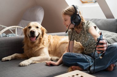 Şirin, küçük gülümseyen kız, Akıllı Telefon Ekranı 'nı Golden Retriever' a gösteriyor.