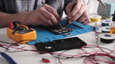 Servis elemanı, Bozuk Akıllı Telefonu Tamir Atölyesinde Tamir Etmek İçin Kontrol Ediyor, Görünümü Kapat