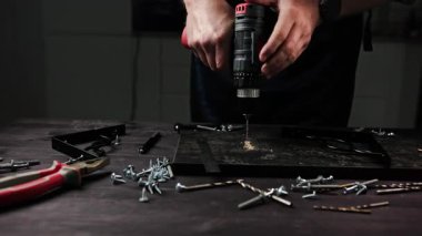 Marangoz, bir ev için siyah parçacık rafı yapmak için atölyede ahşap bir kalas kazıyor.