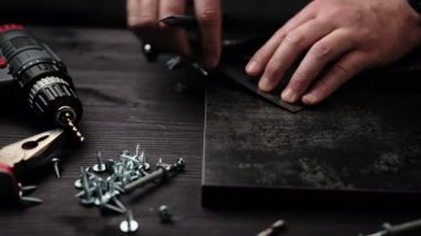 Marangoz, ev rafları yapmak için sondaj yapmak için Siyah Parçacık Tahtasını İşaretliyor