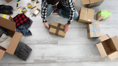 Kız taşınmaya hazırlanmak için karton kutulara kıyafet koyar.