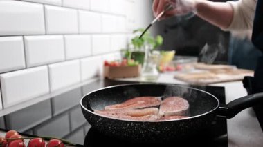 Sağlıklı bir akşam yemeği için kırmızı somon balığını tencerede kızartıyordu.
