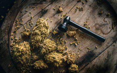 Koyu ahşap tabakta metal tüten pipo ile kuru CBD kenevir