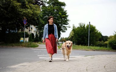 Tasmalı bir kadın yaya geçidinde karşıdan karşıya geçiyor, caddede yürüyor.