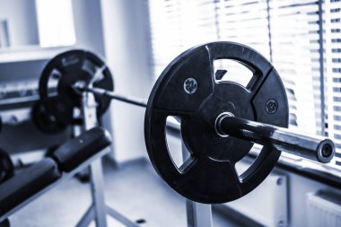 Göğüs presi için ağırlık taşıyan halter spor salonunda.