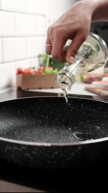 Yemekte sebzeleri kızartmak için tavaya yağ döken kız, dikey video.