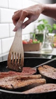 Sağlıklı bir akşam yemeği ve dikey video için mutfakta somon balığını tavada kızartan kız.