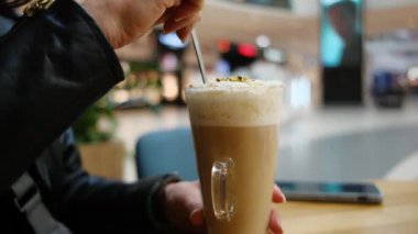 Ticaret merkezindeki bir kafede temiz bir bardakta nefis bir Latte karıştıran bir kız.