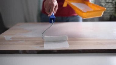 Evdeki tahta tahtayı beyaza boyamak için paten kullanan kız.