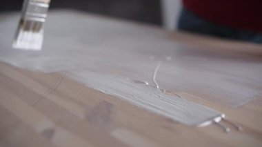 Boya fırçasından çıkan beyaz boya ahşap mobilya yüzeyini kaplıyor.