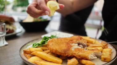 Kafede kızarmış balığın üzerine limon suyu serpiştiren kız.