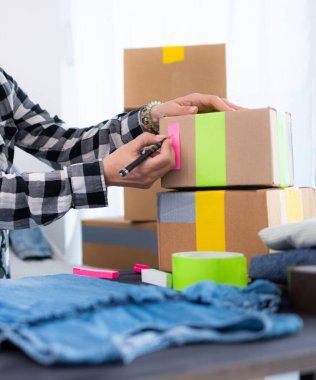 Küçük işletmelerde nakliye ve paketleme ürünleri için karton kutu hazırlayan bir kız.