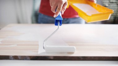 Kız ahşap bir tahtayı paten fırçasıyla beyaza boyuyor