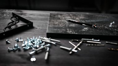 Marangoz, partikül tahtası raf görevi gören bir masanın üzerinde vida ve aletler