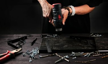 Kız marangoz atölyede ahşap bir kalas delip şık ev rafları yapıyor.