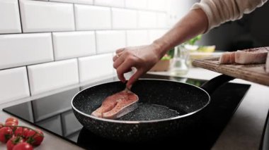 Kırmızı somon balığı parçalarını fırının üstünde tavaya koyan kız.