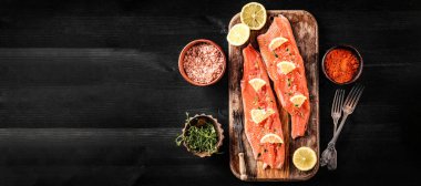 Limonlu ve baharatlı çiğ alabalık filetosu kesim tahtasında pişirmeye hazır.