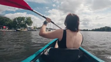 Gölde kürekle kano süren bir kadın aktif olarak açık hava su sporlarına katılıyor.