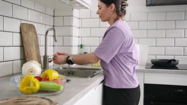 Salata hazırlamak için mutfakta domates ve sebze yıkayan kız.