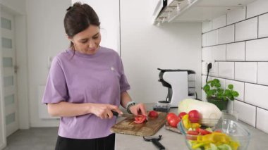 Mutfakta sebze salatası için domates kesen bir kız.