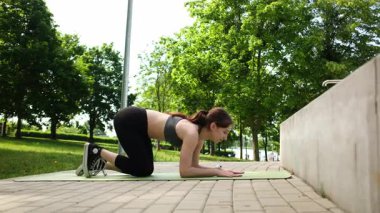 Formda kız spor yapıyor ve parkta esniyor.