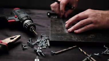 Marangoz, Kara Parçacık Plank 'ından ev rafları yapmak için sondaj tahtasını işaretliyor