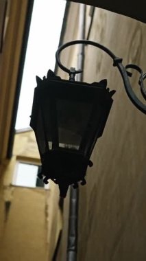 Ortaçağ Avrupa Binası, kemerinde eski bir fener olan dar bir sokakta cephe hattına bakıyor.