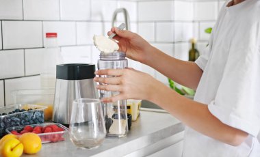 Küçük kız mutfakta bir milkshake 'e dondurma ekliyor.